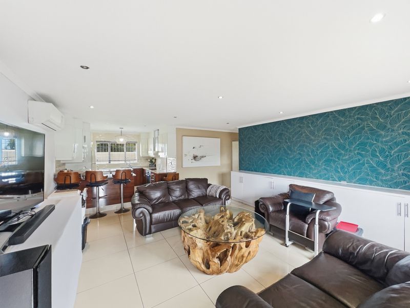 Spacious open-plan living and kitchen area featuring tiled floors, modern built-in cabinetry, and a feature wall, creating a functional and cohesive living space.