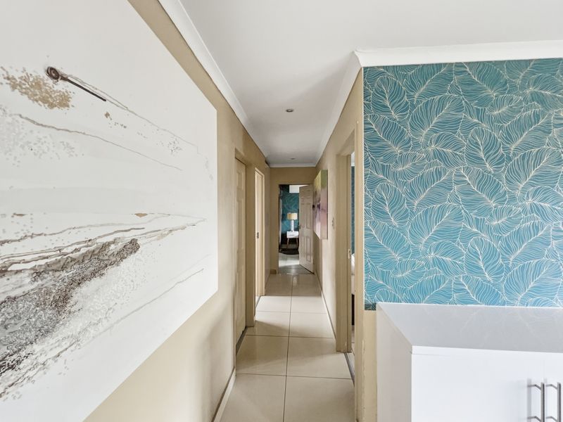 A well-lit hallway featuring tiled flooring, decorative wallpaper, and access to multiple internal rooms.
