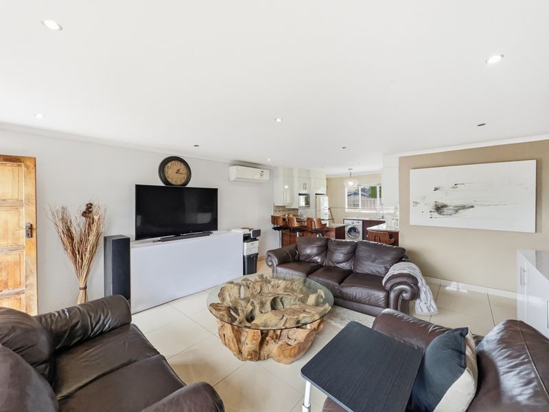 Spacious open-plan living area featuring tiled floors, recessed lighting, and a modern kitchen with integrated cabinetry and appliances.