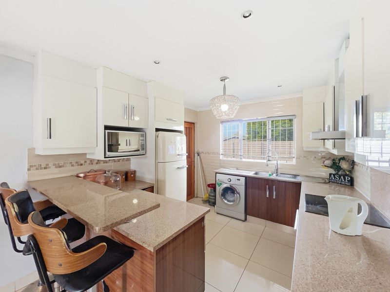Modern kitchen featuring granite countertops, ample built-in cabinetry, a breakfast bar, and integrated appliances, offering a functional and well-lit cooking space.