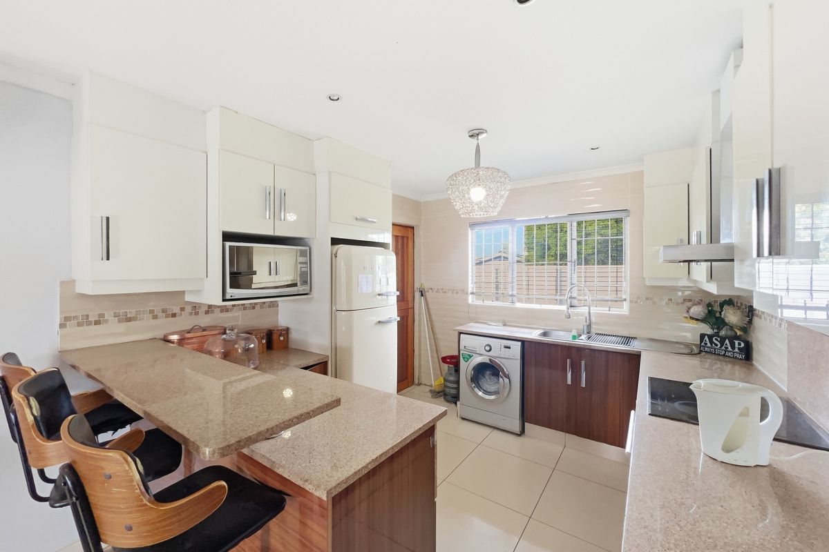 Modern kitchen featuring granite countertops, ample built-in cabinetry, a breakfast bar, and integrated appliances, offering a functional and well-lit cooking space.