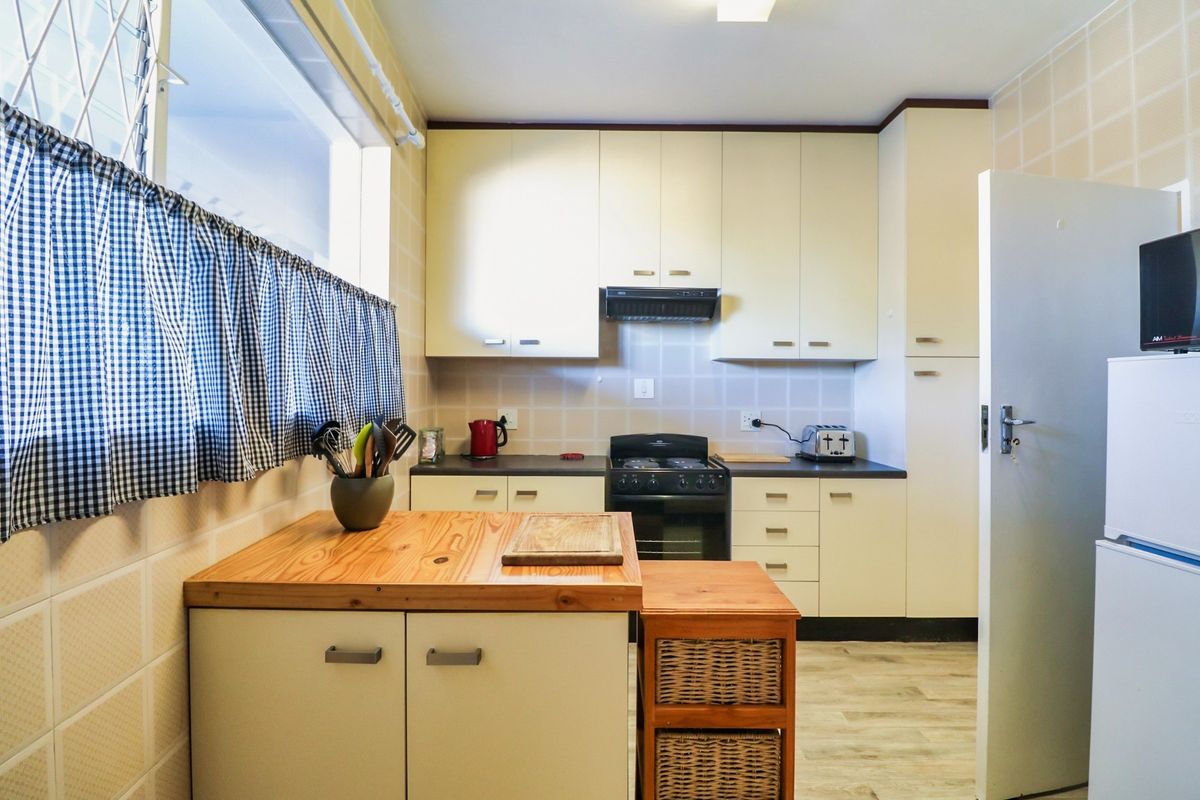 A functional kitchen featuring built-in cabinetry, a tiled backsplash, and a freestanding stove, offering a practical layout for daily meal preparation.