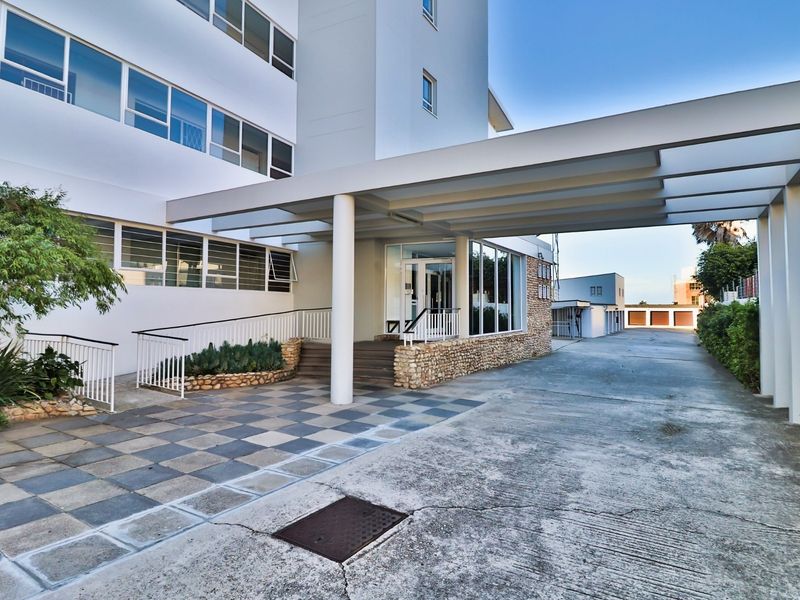The front entrance of the apartment building features a covered walkway, stone accents, and a paved approach with a concrete driveway.