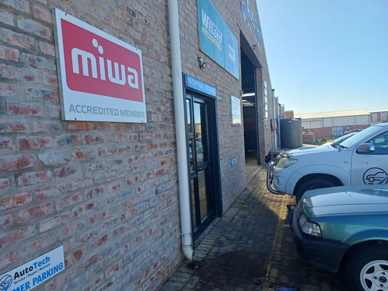 Front exterior view of an industrial property featuring exposed brickwork, a dedicated reception entrance, and paved driveway access.