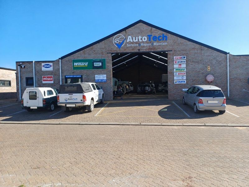 Front elevation of an industrial workshop facility featuring brick construction, large open bay access, and paved parking area.
