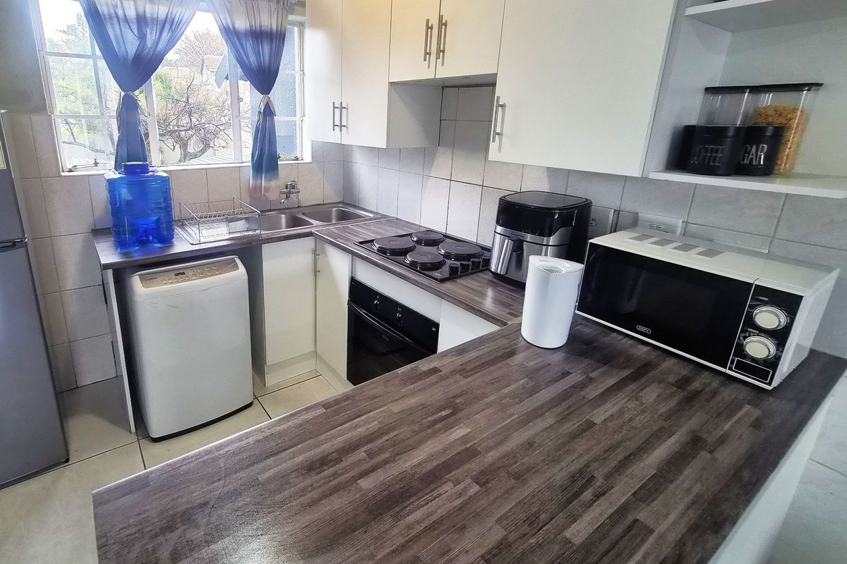 A functional kitchen featuring laminate countertops, built-in cabinetry, a tiled backsplash, and integrated cooking appliances, offering a clean and practical workspace.