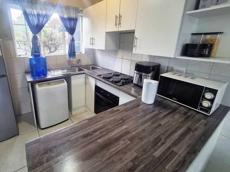 A functional kitchen featuring laminate countertops, built-in cabinetry, a tiled backsplash, and integrated cooking appliances, offering a clean and practical workspace.