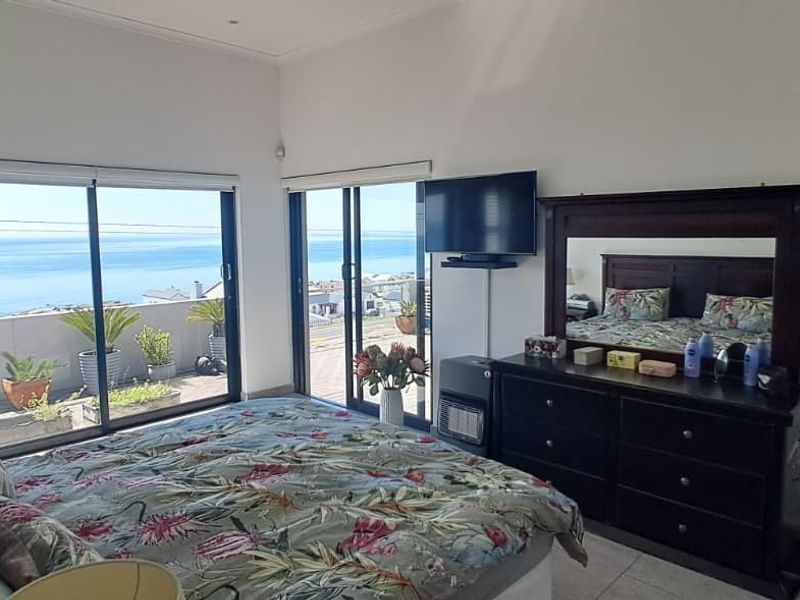 Spacious bedroom featuring large sliding glass doors that open onto a balcony with expansive ocean views and tiled flooring throughout.