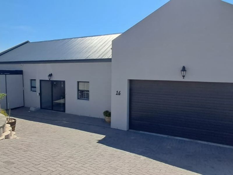 Front elevation of a modern house featuring a paved driveway, a single sectional garage door, and a clean, neutral-toned exterior facade.
