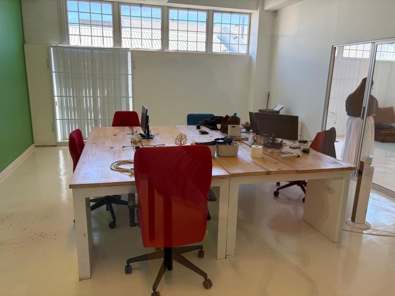 A bright, open-plan office space featuring high-level multi-pane windows, durable epoxy flooring, and a modern glass partition wall.