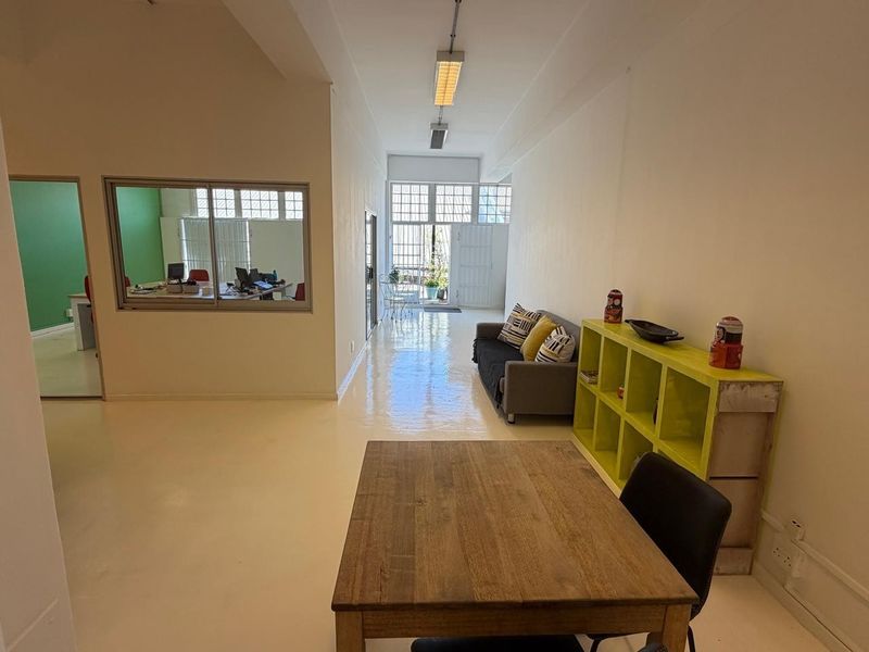 A bright, open-plan office space featuring high ceilings, polished epoxy flooring, and an internal glass partition providing visibility into an adjacent workspace.