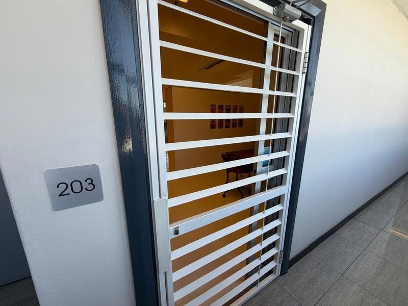 Office entrance featuring a secure metal gate, door closer, and clear unit number signage in a well-maintained hallway.