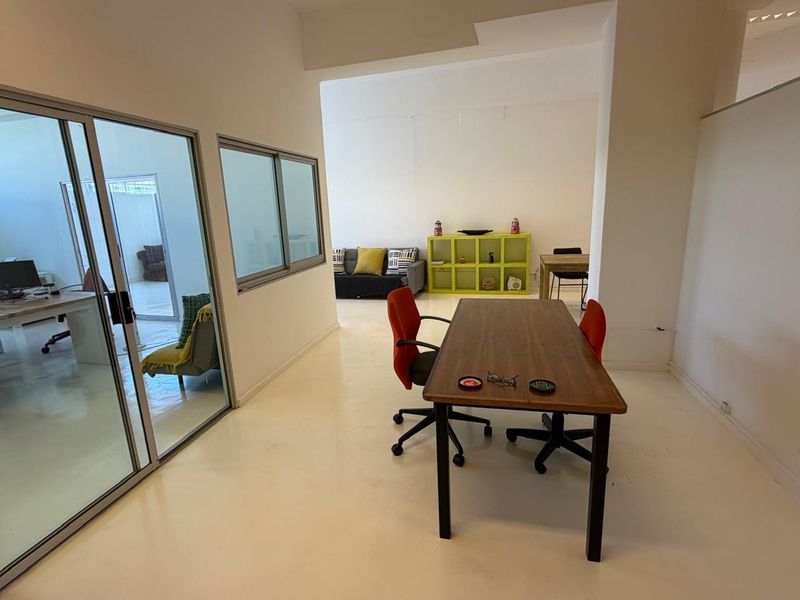 Open-plan office space featuring polished epoxy flooring and a sliding glass partition wall, providing a bright and flexible work environment.