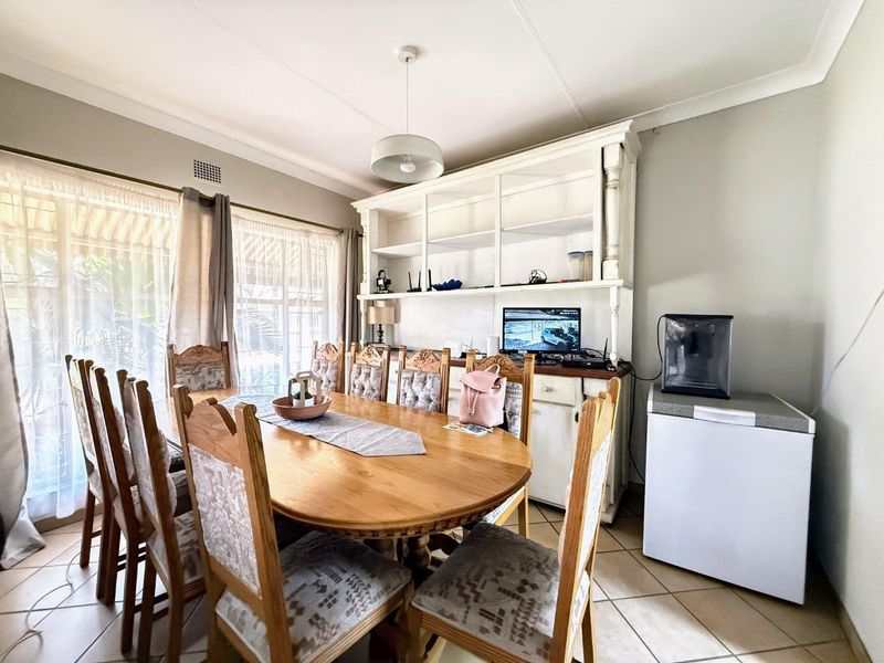 A dining room featuring tiled flooring, a built-in display cabinet, and a sliding glass door providing natural light.