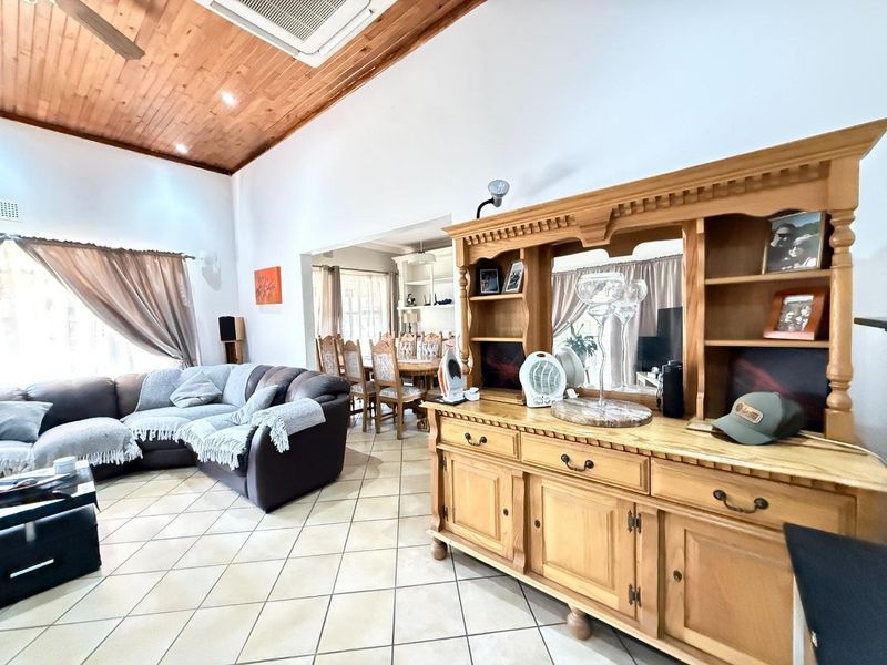 Spacious open-plan living and dining area featuring a high timber-clad vaulted ceiling, ceramic tiled flooring, and integrated recessed lighting.