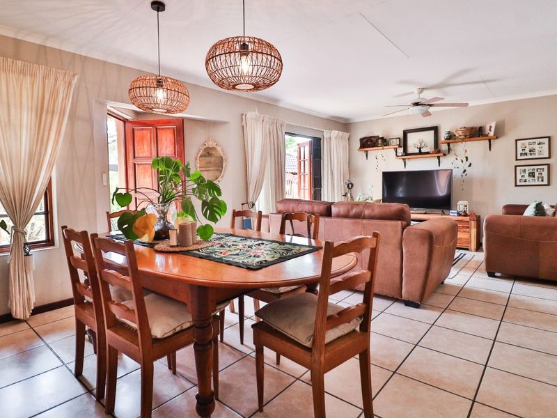 Spacious open-plan living and dining area featuring tiled flooring, ceiling fan, and direct access to outdoor spaces through timber-framed doors.