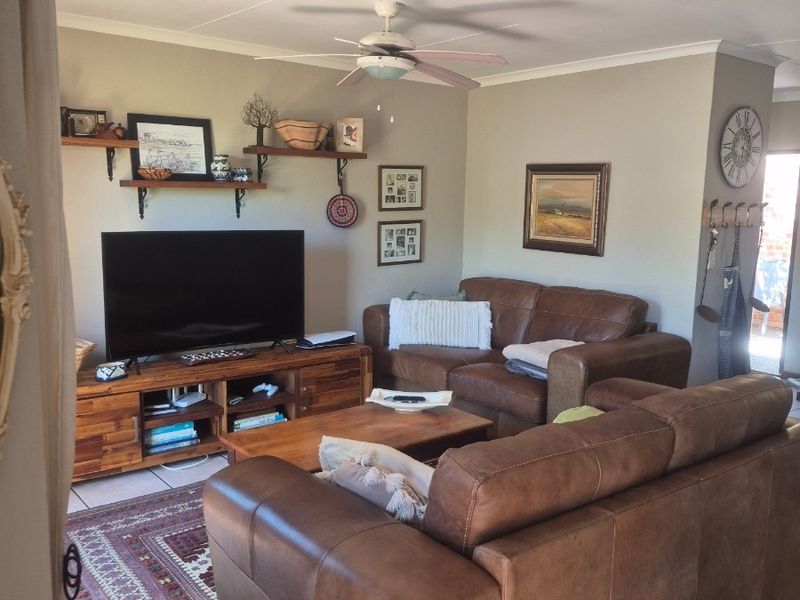 A comfortable living room featuring tiled flooring, a ceiling fan, and coved cornicing, providing a functional and well-maintained space for relaxation.