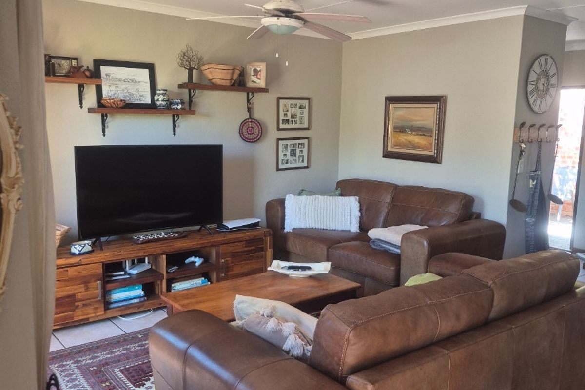 A comfortable living room featuring tiled flooring, a ceiling fan, and coved cornicing, providing a functional and well-maintained space for relaxation.