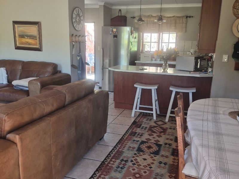 Open-plan living and kitchen area featuring tiled flooring, a central kitchen island with breakfast bar seating, and integrated cabinetry.