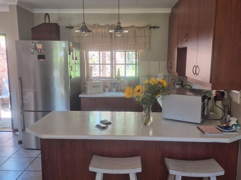 A functional kitchen featuring wooden cabinetry, a central island with breakfast bar seating, and tiled flooring, offering a practical layout for daily use.