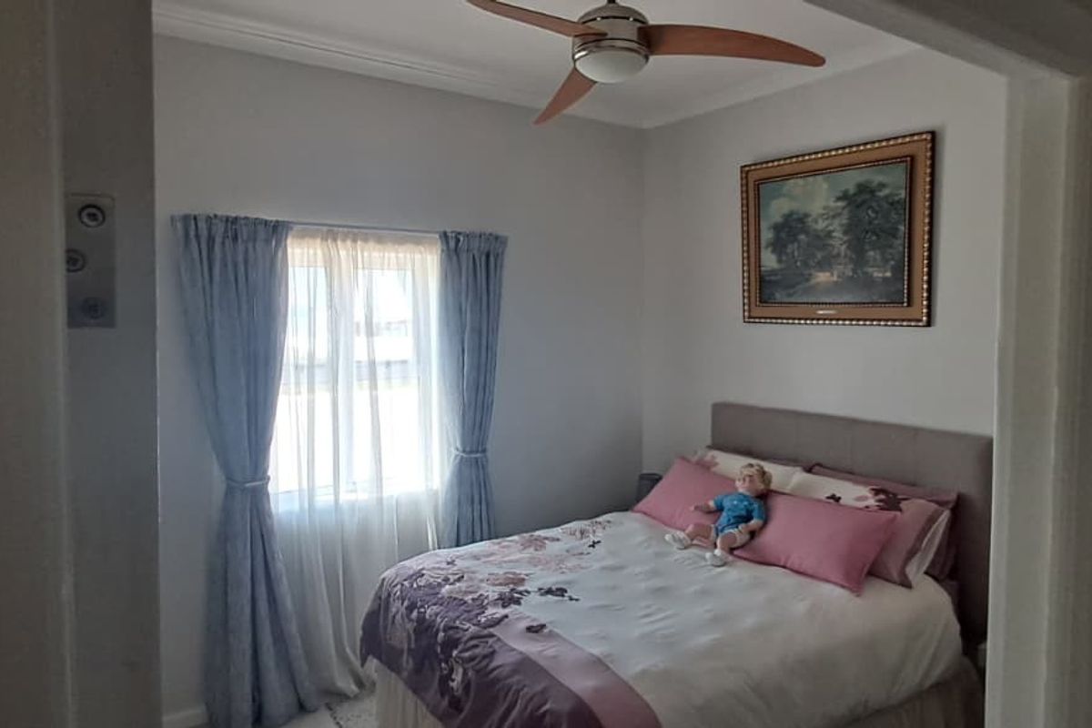 A cozy bedroom featuring a ceiling fan and crown molding, providing a comfortable and functional sleeping space.