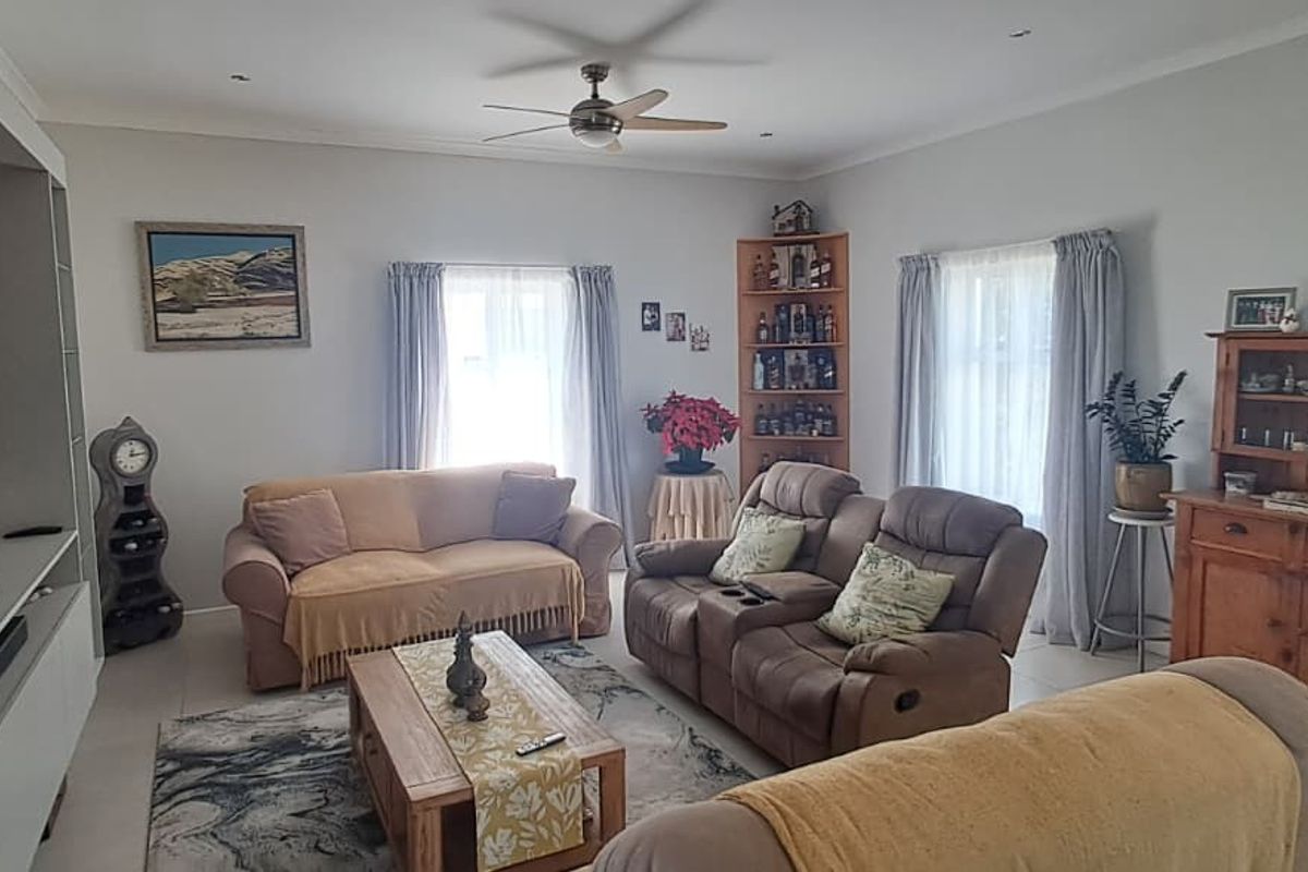 A comfortable living room featuring a built-in media unit, tiled flooring, and a ceiling fan, offering a functional and well-maintained space.