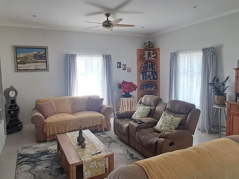 A comfortable living room featuring a built-in media unit, tiled flooring, and a ceiling fan, offering a functional and well-maintained space.