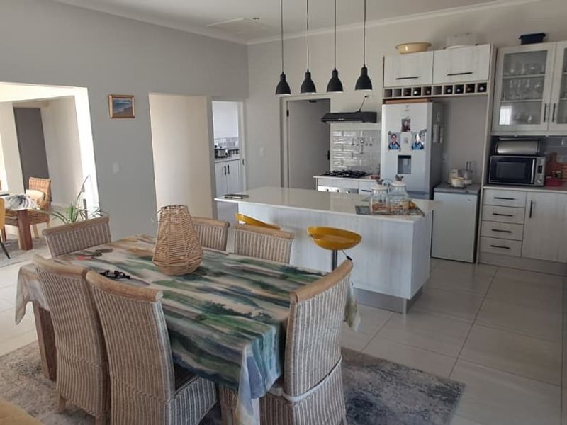 Spacious open-plan kitchen and dining area featuring a central island, modern cabinetry, tiled flooring, and an adjacent indoor fireplace area.
