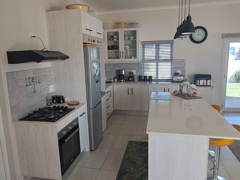 Modern open-plan kitchen featuring a central island, stone countertops, gas hob, built-in oven, and direct access to the outdoor patio area.