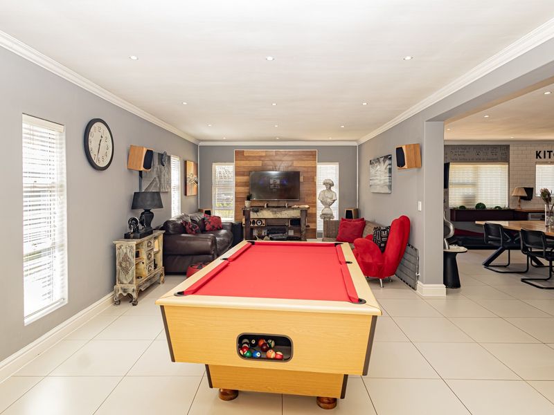 Spacious open-plan living area featuring tiled floors, recessed lighting, and a wood-accented feature wall, seamlessly connecting to the adjacent dining and kitchen space.