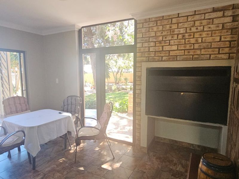 Enclosed patio area featuring a built-in braai, tiled flooring, and large sliding glass doors providing direct access to the garden.