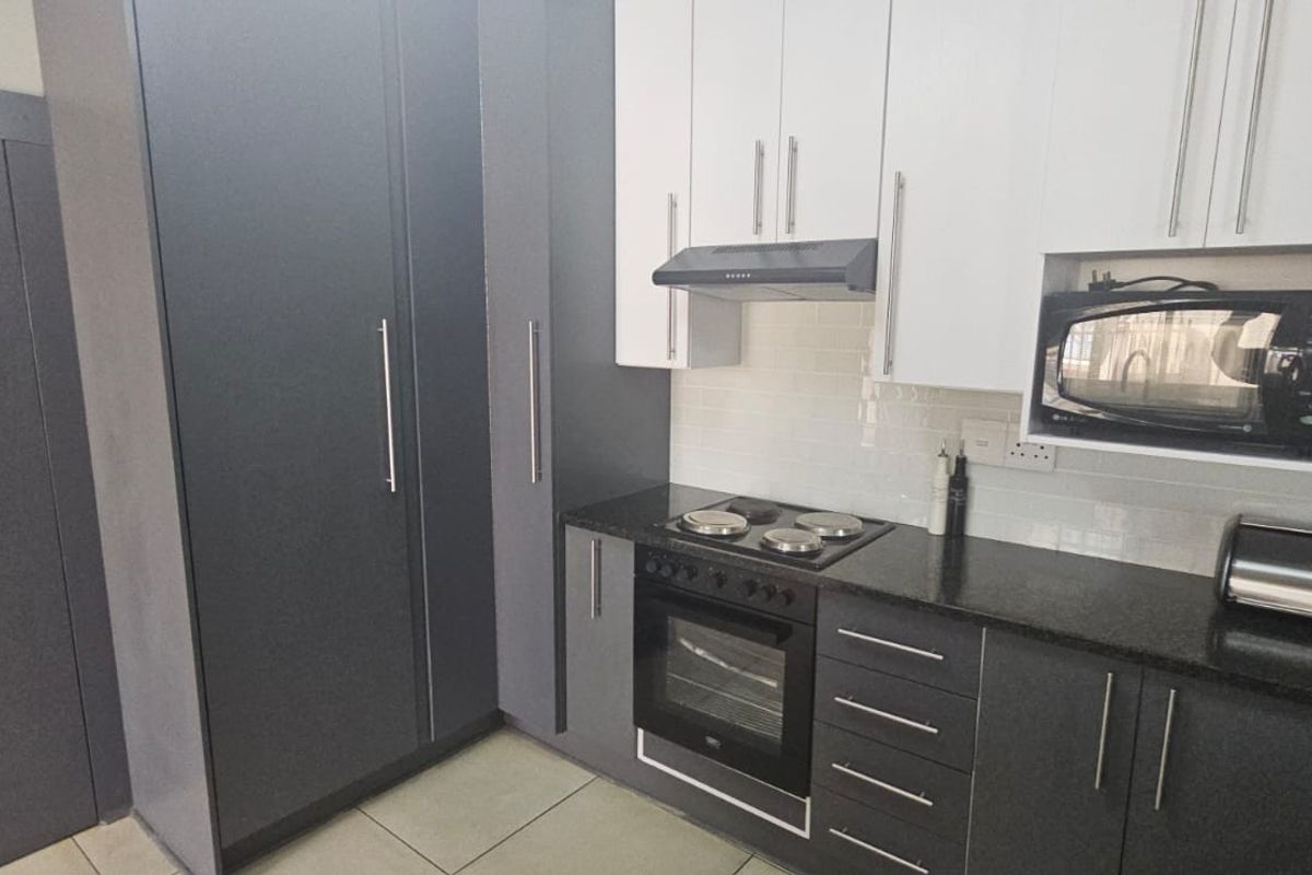 Modern kitchen featuring two-tone cabinetry, granite countertops, subway tile backsplash, and integrated appliances including an oven, hob, and microwave.