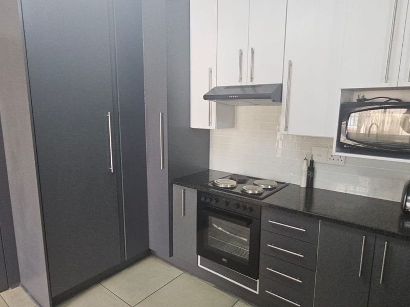 Modern kitchen featuring two-tone cabinetry, granite countertops, subway tile backsplash, and integrated appliances including an oven, hob, and microwave.