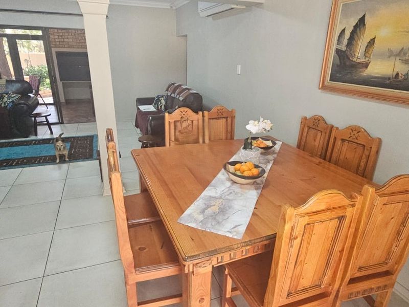 Open-plan living and dining area featuring tiled flooring, a breakfast bar, and a wall-mounted split-system air conditioner.
