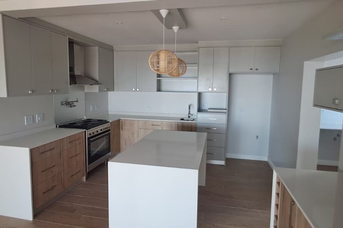 Modern kitchen featuring two-tone cabinetry, a central island with quartz countertops, stainless steel oven, extractor fan, and tiled flooring in an open-plan layout.