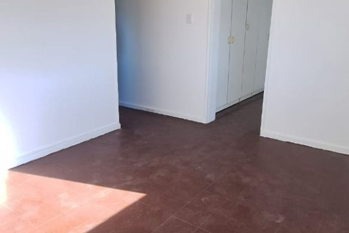 An empty living area featuring tiled flooring and built-in storage cupboards, offering a blank canvas for renovation or interior design updates.