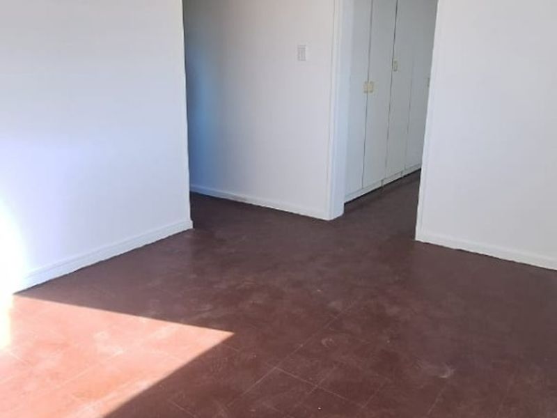 An empty living area featuring tiled flooring and built-in storage cupboards, offering a blank canvas for renovation or interior design updates.