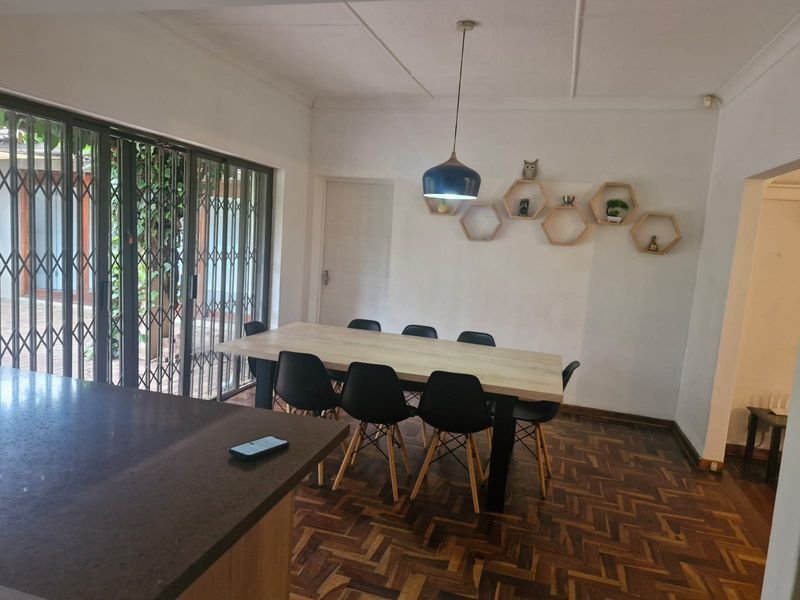Dining area featuring classic parquet flooring, a modern pendant light, and large sliding glass doors providing access to the outdoor space.