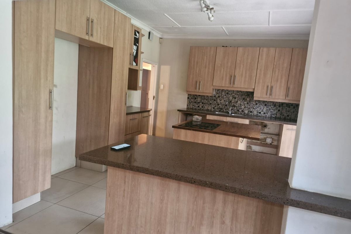 A functional kitchen featuring light wood-look cabinetry, stone countertops, and a mosaic tile backsplash, currently requiring minor repairs to cabinetry.