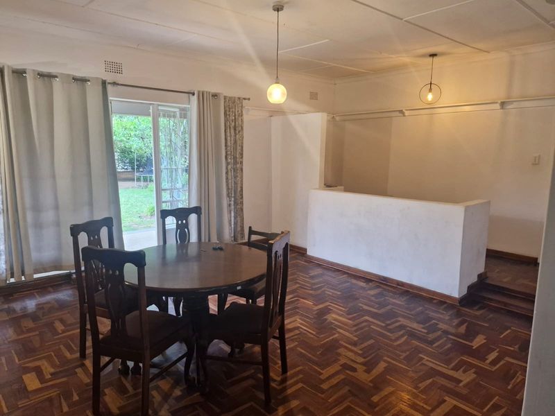 Spacious living area featuring classic herringbone parquet flooring, pendant lighting, and a sliding glass door providing direct access to the garden.