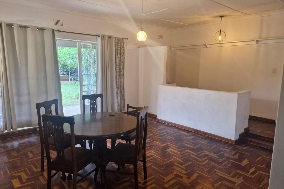 Spacious living area featuring classic herringbone parquet flooring, pendant lighting, and a sliding glass door providing direct access to the garden.