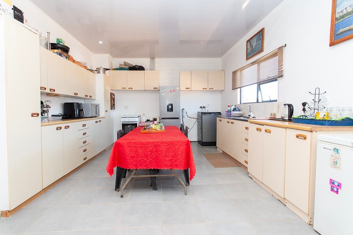 Spacious kitchen featuring ample built-in cabinetry, laminate countertops, a double sink, and tiled flooring, offering a functional layout for daily meal preparation.