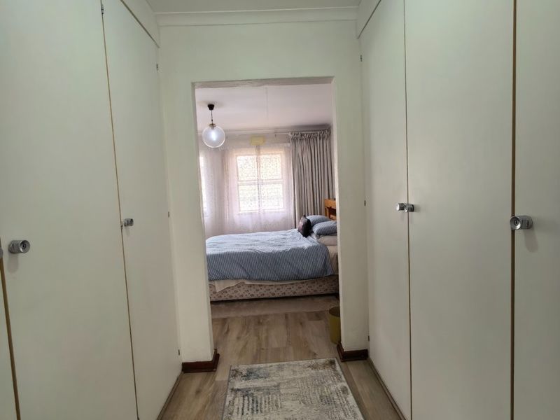 A functional hallway featuring extensive built-in cupboard storage and laminate flooring, providing a clean transition between living spaces.