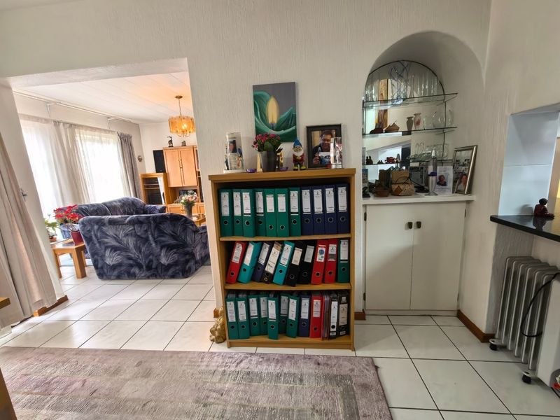 Open plan living area featuring tiled flooring and a built-in arched display cabinet with glass shelving, connecting to the main lounge space.