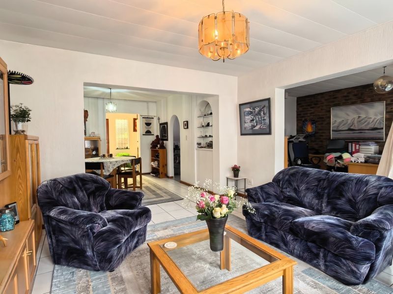 Spacious open-plan living area featuring tiled floors, built-in arched shelving, and an exposed brick feature wall, creating a versatile and connected living space.