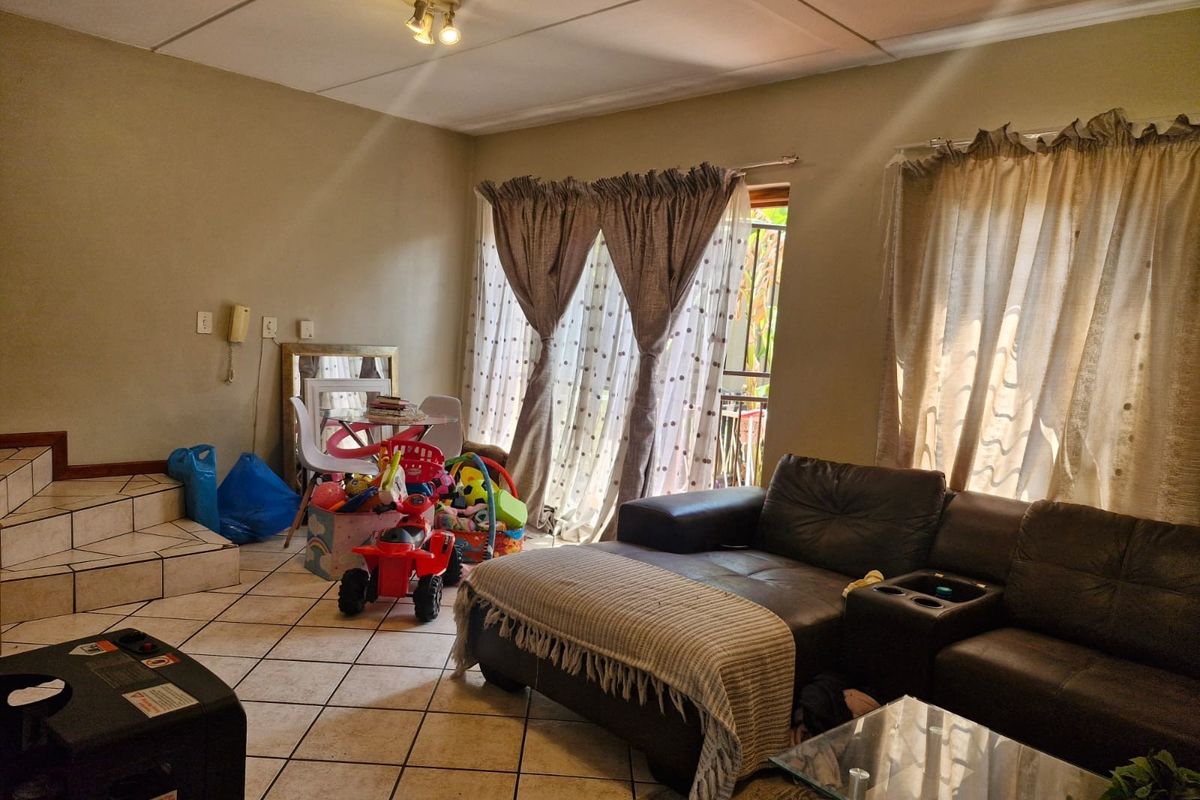 A living room featuring tiled flooring and a sliding glass door providing access to the exterior.