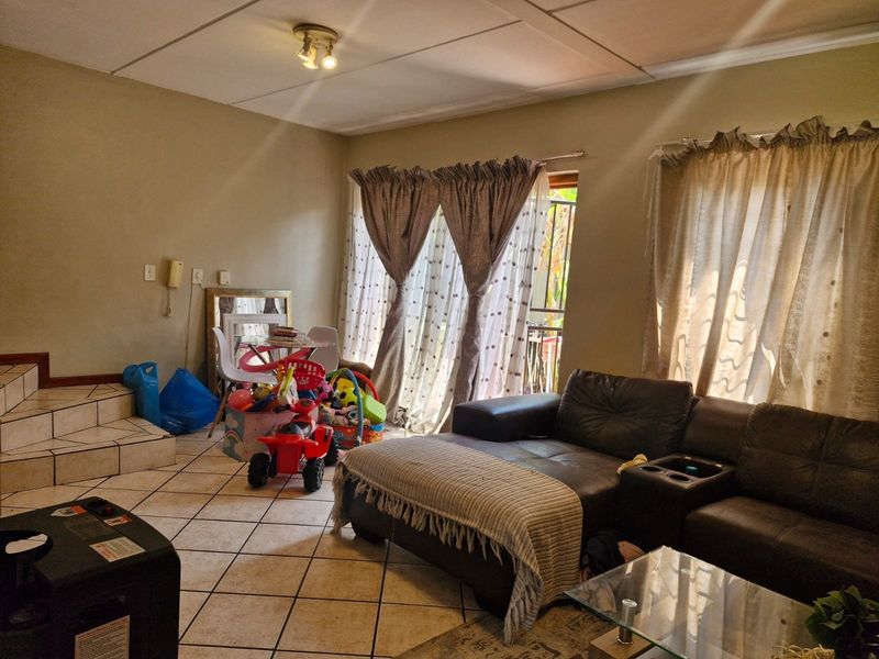 A living room featuring tiled flooring and a sliding glass door providing access to the exterior.