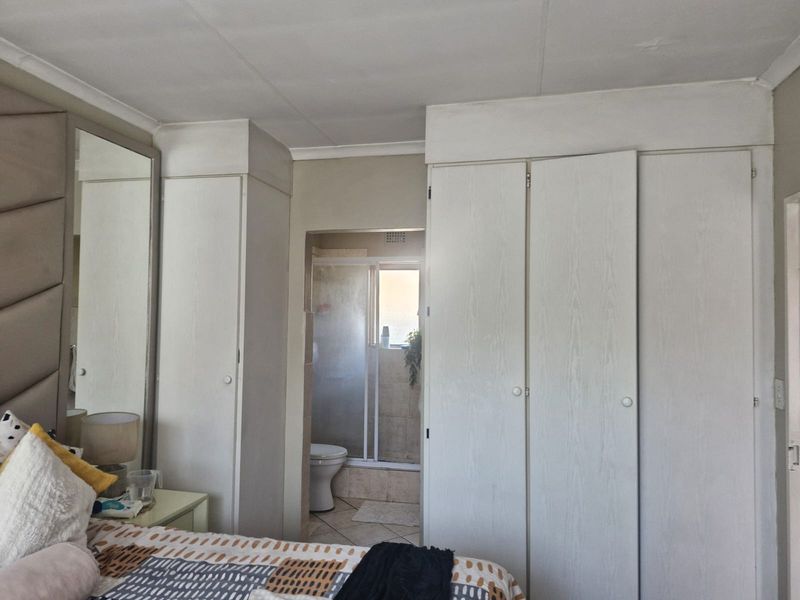 Bedroom featuring built-in cupboards and direct access to an en-suite bathroom with a shower enclosure.
