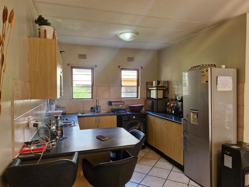 A functional kitchen featuring laminate cabinetry, dark countertops, tiled backsplash, and integrated appliances, offering a practical layout with potential for modern cosmetic updates.