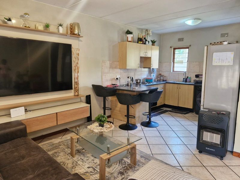 Open-plan living and kitchen area featuring tiled flooring, built-in cabinetry, and a dedicated media wall unit.